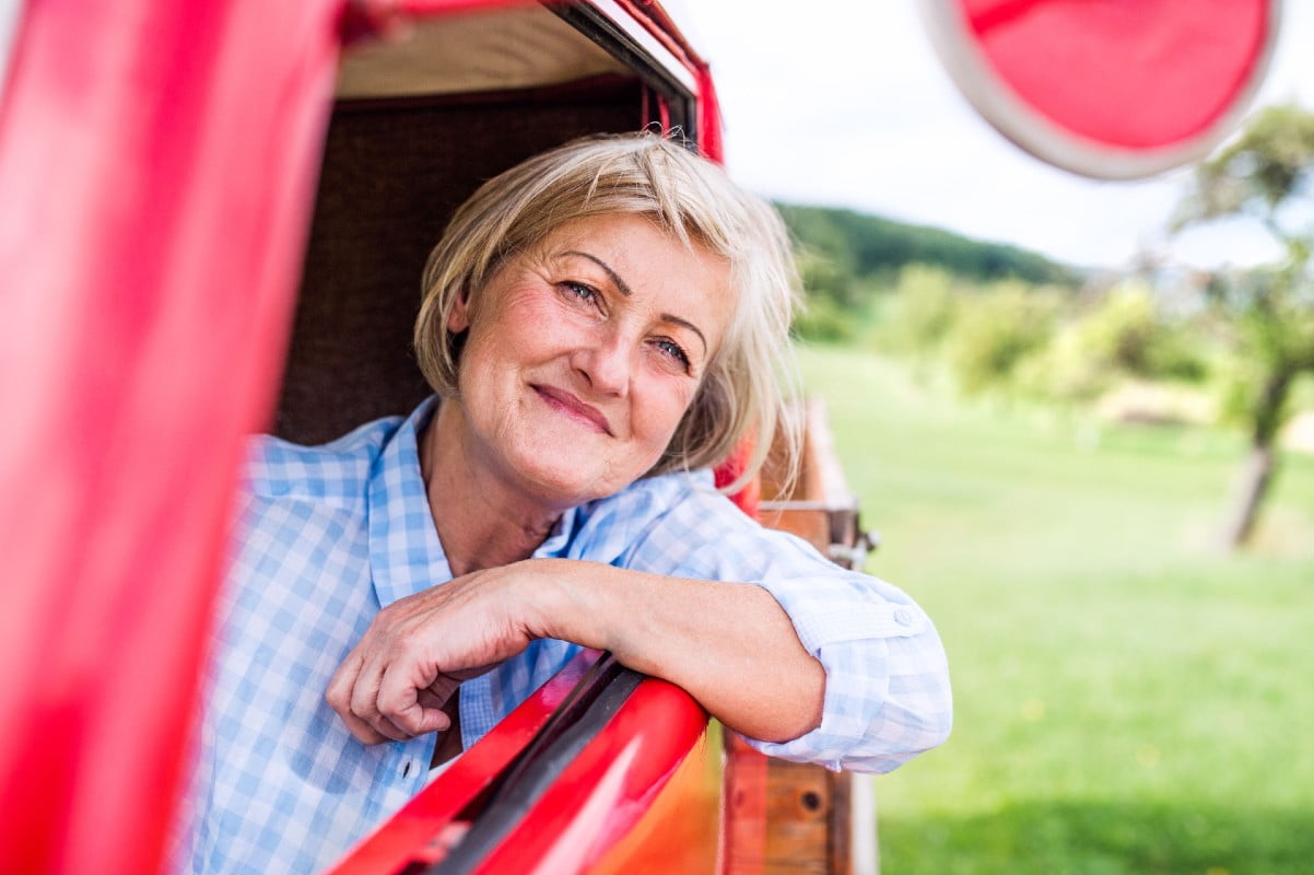 Close up of content farmer woman in checked blue shirt inside vintage pickup truck